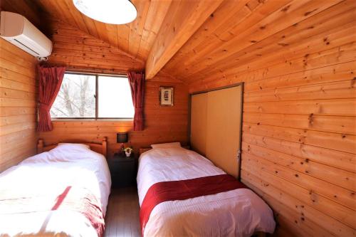 a bedroom with two beds in a log cabin at 湖畔まで徒歩圏内、BBQ可能！隠れ家感溢れる【Nハウス】 in Yamanakako