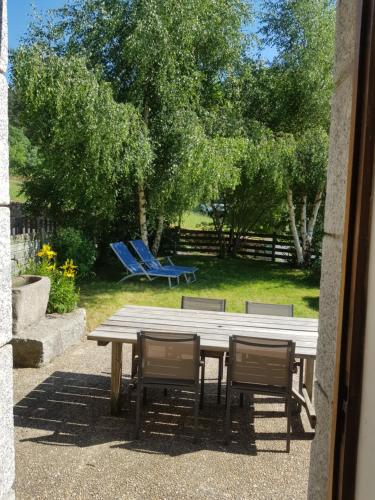 - une table de pique-nique en bois avec trois chaises et un banc dans l'établissement Gîte à la campagne 3 * proche A75 en Margeride., à La Roche