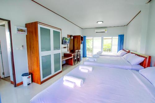 a room with four beds with white sheets and a tv at Meena Resort in Chanthaburi