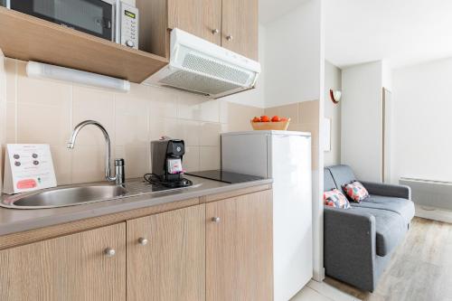 a small kitchen with a sink and a refrigerator at Appart'City Confort Le Mans Centre in Le Mans