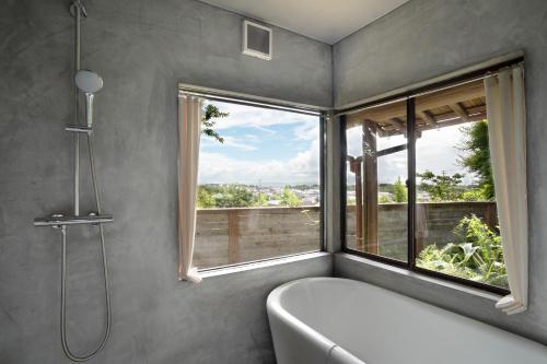 a bathroom with a bath tub and a window at HAZcottage in Makinohara