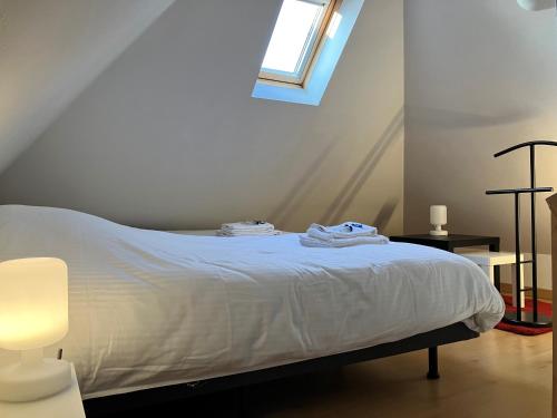 a bedroom with a bed with white sheets and a window at Duplex in hartje Brugge met ruim zonneterras 2p in Bruges