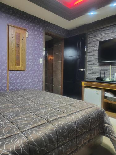 um quarto com uma cama e uma televisão na parede em Gohyeon Ace motel em Geoje