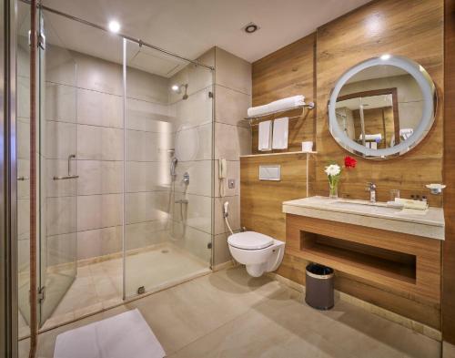 a bathroom with a shower and a toilet and a sink at Hotel Hindusthan International, Bhubaneswar in Bhubaneshwar