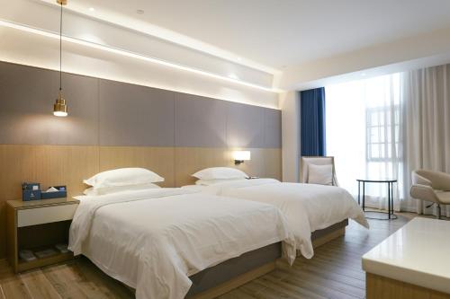a bedroom with two beds and a large window at Paco Hotel Guangzhou North Railway Station in Huadu