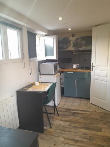 une petite cuisine avec une table et un micro-ondes dans l'établissement Studio paisible orsay, à Orsay