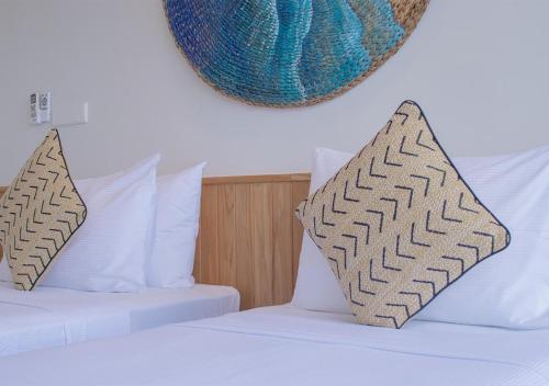 two beds with white sheets and pillows in a room at Stone Beach Club in Dhiffushi