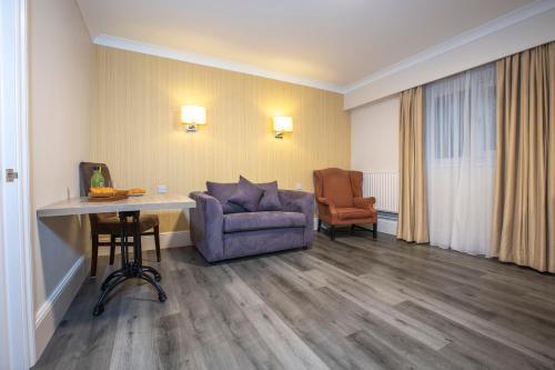 a room with a couch and a chair and a table at Best Western Manor Hotel in Gravesend