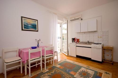 kuchnia ze stołem, różowym stołem i krzesłami w obiekcie Apartments Vila Miranda w mieście Barbat na Rabu