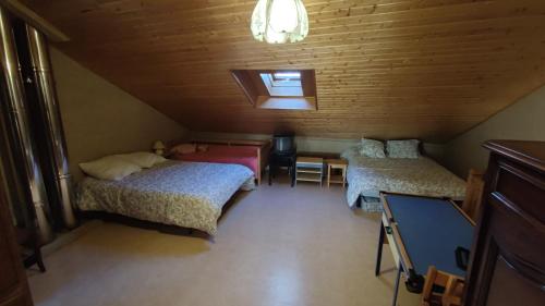 une chambre mansardée avec deux lits, une table et un bureau dans l'établissement Maison Cal Vi, à Saint-Pierre-dels-Forcats