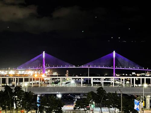 a large building with a purple bridge at night at Brown Suites Busan Station in Busan