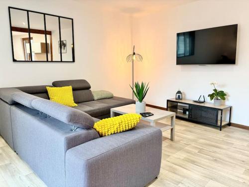 ein Wohnzimmer mit einem Sofa und einem TV in der Unterkunft Gîte de la Fontaine Charmante maison au cœur de Beblenheim - Route des vins in Beblenheim