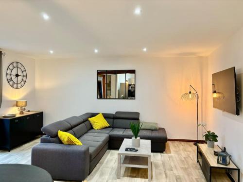 ein Wohnzimmer mit einem grauen Sofa und gelben Kissen in der Unterkunft Gîte de la Fontaine Charmante maison au cœur de Beblenheim - Route des vins in Beblenheim