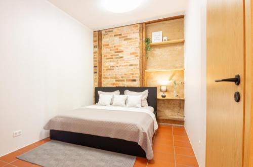 een slaapkamer met een bed en een bakstenen muur bij Gildi Apartment in Tartu