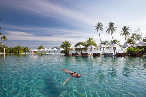 a person swimming in the water at a resort at Pullman Phuket Panwa Beach Resort in Panwa Beach