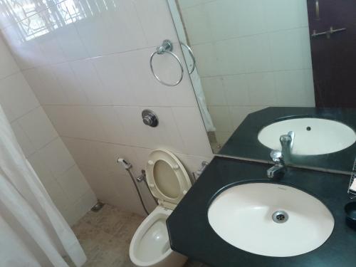 a bathroom with a sink and a toilet and a mirror at Urban Retreat Homestay in Mangalore