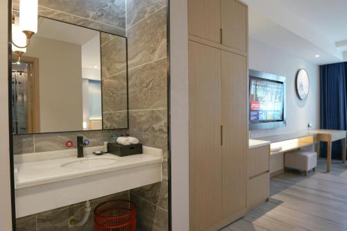 a bathroom with a sink and a mirror at Paco Hotel Guangzhou North Railway Station in Huadu