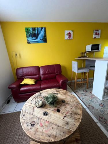 sala de estar con sofá rojo y mesa de madera en Les Salines, en Montmorot