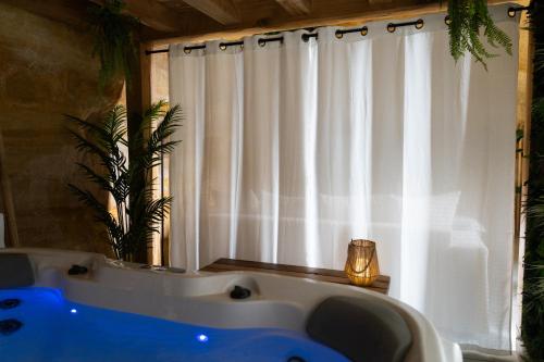 baño con una gran bañera blanca y ventana en Le temps suspendu, Suite troglodyte & SPA privé, en Doué-la-Fontaine