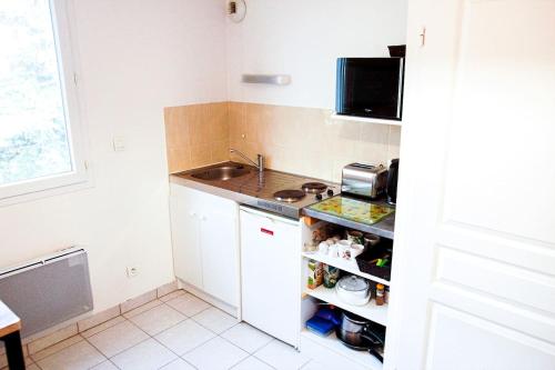 une petite cuisine avec des armoires blanches et un évier dans l'établissement Proche rempart avec Parking sécurisé, à Avignon