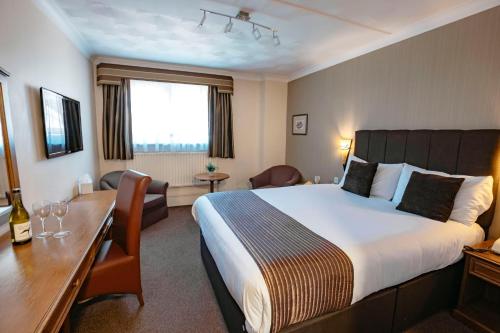 a hotel room with a large bed and a desk at Best Western Manor Hotel in Gravesend
