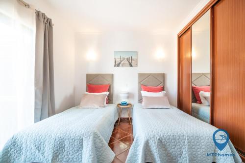 een slaapkamer met 2 bedden en een spiegel bij Casa Nico a 3 minutos da praia in Albufeira