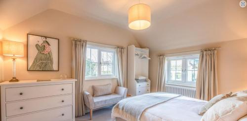 a bedroom with a bed and a chair and windows at The Lodge, Saxmundham in Saxmundham