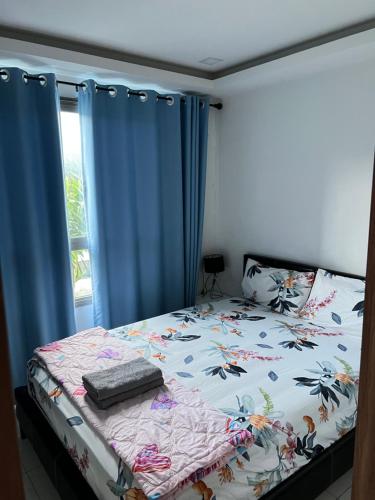 a bed in a bedroom with blue curtains at Arcadia Beach Resort Condominium in Pattaya South