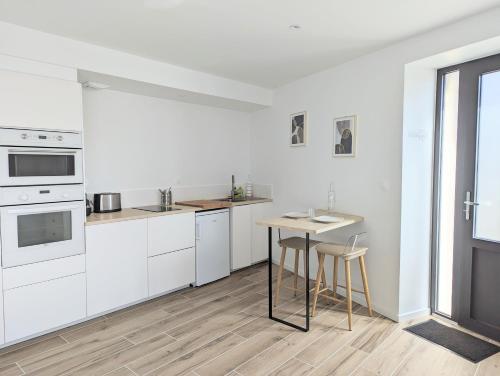 une cuisine avec des armoires blanches et une table et des chaises dans l'établissement Le Brûlis - La nature en ville, à Nantes