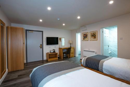 a hotel room with two beds and a television at Best Western Manor Hotel in Gravesend