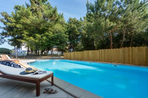 a swimming pool in a yard with a wooden fence at Hôtel Valdys Thalasso & Spa - les Pins in Saint-Jean-de-Monts