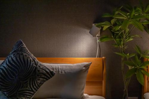 a bed with a pillow and a plant next to a lamp at KUROMON Royal in Osaka