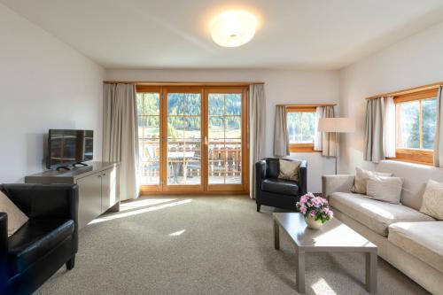a living room with a couch and a tv at Hotel Allegra in Zuoz