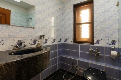 ein Bad mit einem Waschbecken, einem WC und einem Fenster in der Unterkunft Theta Villa in Alībāg