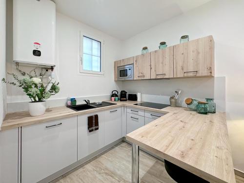 une cuisine avec des armoires blanches et une table en bois dans l'établissement Tivoli 2 - Renovated studio, Monaco Border, 5mn from Casino Monte Carlo, à Beausoleil