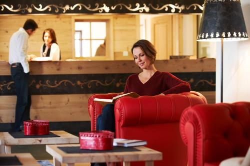 a woman sitting in a red chair reading a book at Zin Senfter Residence in San Candido