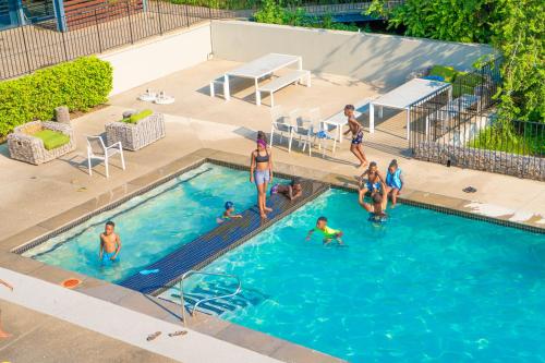 un groupe de personnes jouant dans une piscine dans l'établissement 1 Harriet Place - Beautiful Self Catering 2 bedroom unit next to Carlswald Lifestyle Shopping Centre with free WiFi, Onsite Restaurant & Swimming Pool- Perfect for a small family in Midrand Carlswald, à Midrand