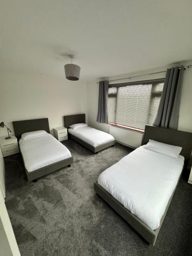 a room with three beds and a window at Contractor and Family, Private Detached Property DY5 in Brettell Lane