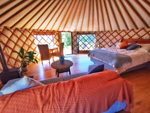a yurt bedroom with two beds and a table at Petal Creek Farm in Tarakohe