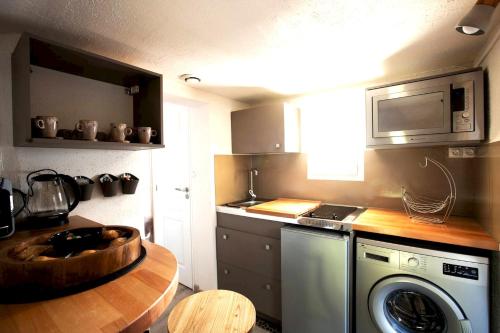 La cuisine est équipée d'une table, d'un four micro-ondes et d'un lave-vaisselle. dans l'établissement Appartement cosy à Clermont-Ferrand 35 m² proche commodités, à Clermont-Ferrand