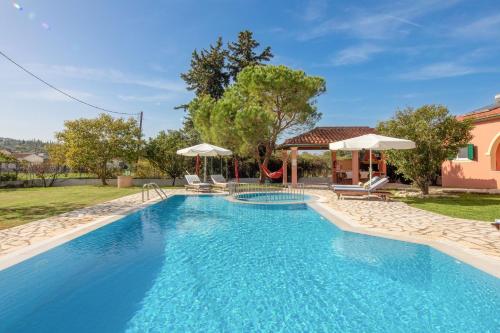 a pool with chairs and umbrellas next to a house at Bella Villa Vasiliki in Litherés