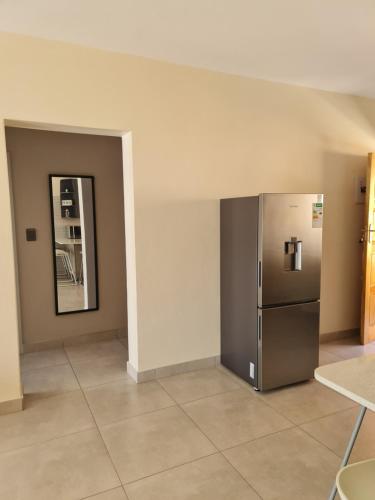 a empty room with a refrigerator and a mirror at Cozy Apartment Jhb South in Johannesburg
