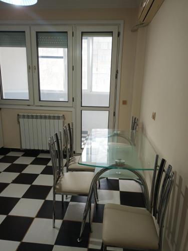 a glass table and chairs in a room with a checkered floor at Апартамент Първанова in Montana