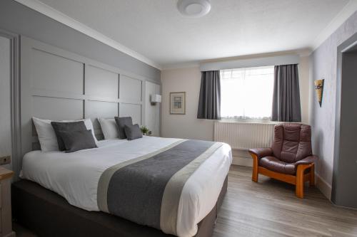 a bedroom with a large bed and a chair at Best Western Manor Hotel in Gravesend