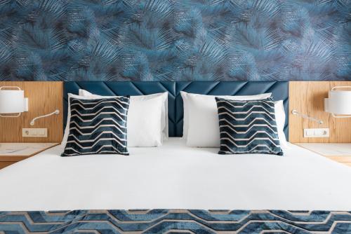 a bedroom with a bed with pillows and a blue headboard at Eurostars Matosinhos in Matosinhos