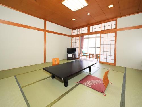 a living room with a table and a chair at 多武峰観光ホテル in Sakurai