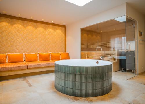 a large bathroom with a tub and a couch at Spa & Resort Bachmair Weissach, LUXURY FAMILY RESORT in Rottach-Egern