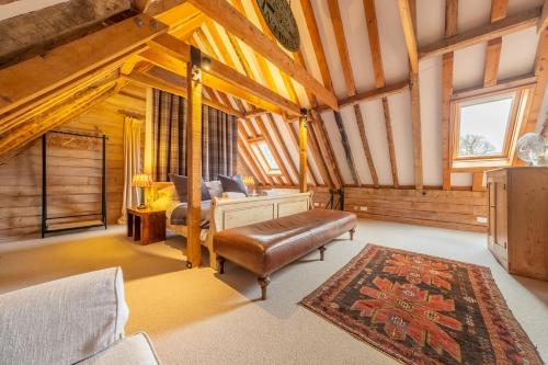 a room with a bed and a couch and a rug at Huge luxury loft cottage in historic country estate - Belchamp Hall Hayloft in Belchamp Otten