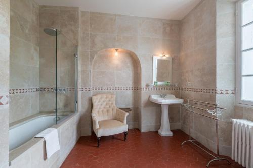 La salle de bains est pourvue d'une baignoire, d'un lavabo et d'une chaise. dans l'établissement Domaine des Fleurs - 8 bedroom estate with private tennis court, à Grasse
