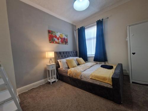 沃爾森德的住宿－Executive 2-Bedroom House in Wallsend，一间卧室配有一张带蓝色窗帘的床和一扇窗户
